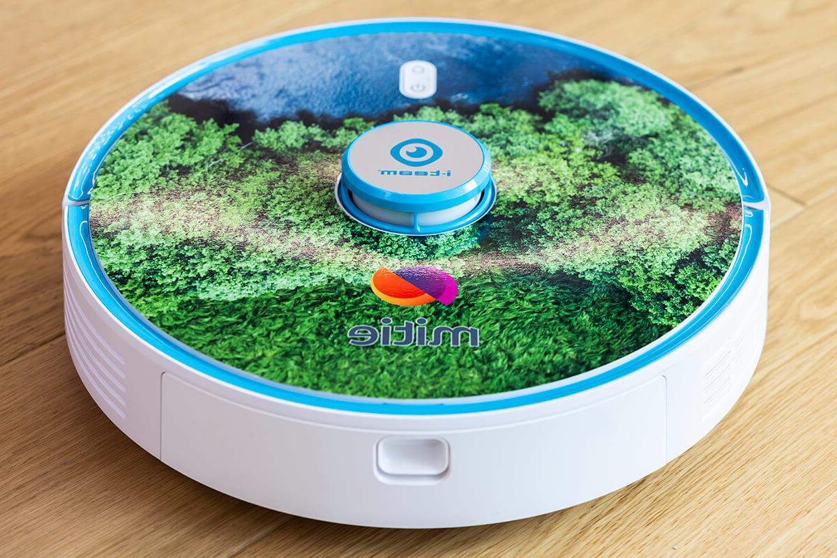 A round robot hoover, with Mitie branding and a print of green trees on the top